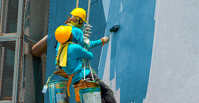 pintores descendo pela corda pintando um prédio branco de azul